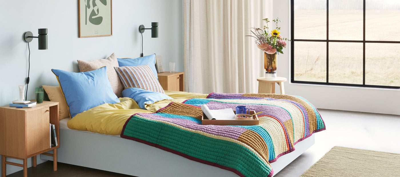 bed with colourful stripe throw and cushions